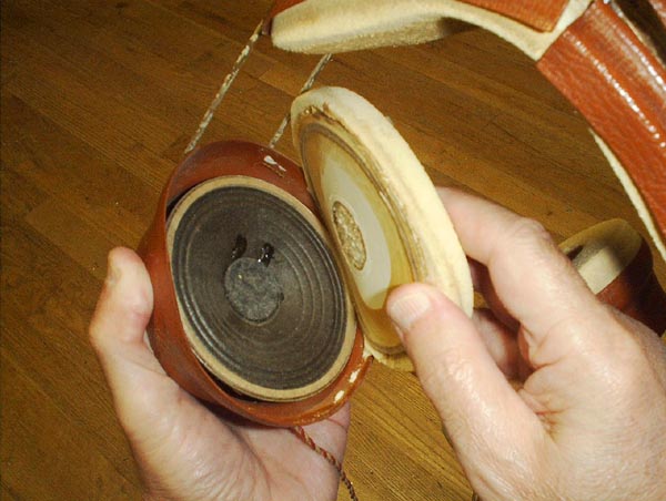  Headphones with ear pad pulled back and small speaker showing inside.