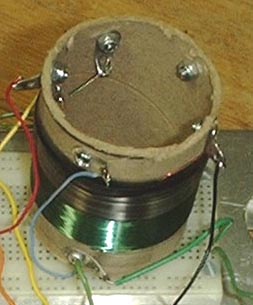 Coil sitting on breadboard showing solder lugs on the inside as well as on the outside.